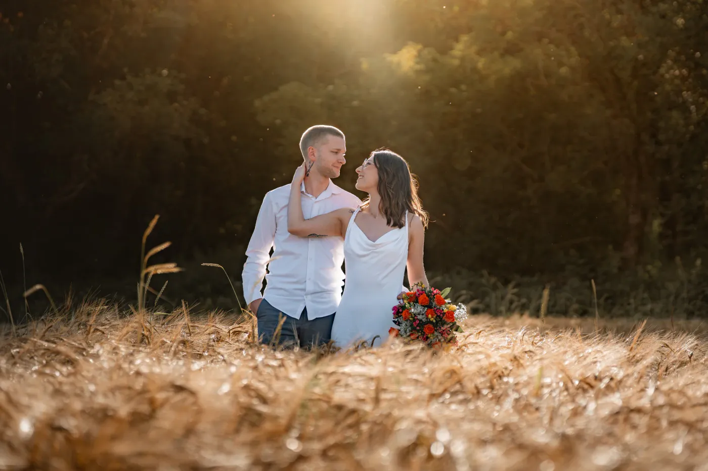 Couple complice dans un champ doré, bouquet à la main, près de Durbuy