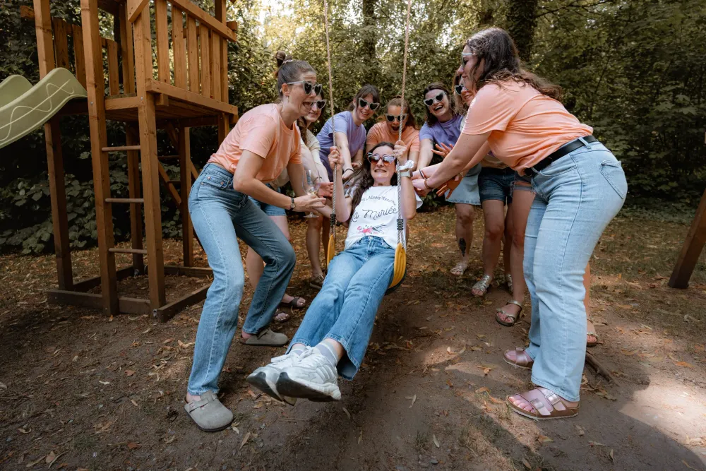 Les amies poussent la future mariée sur une balançoire, en plein fou rire