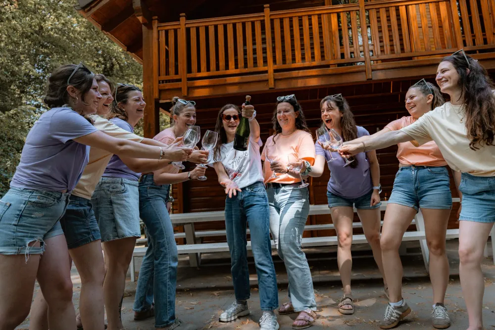 Toast au champagne devant un chalet en bois, cierge magique à la main